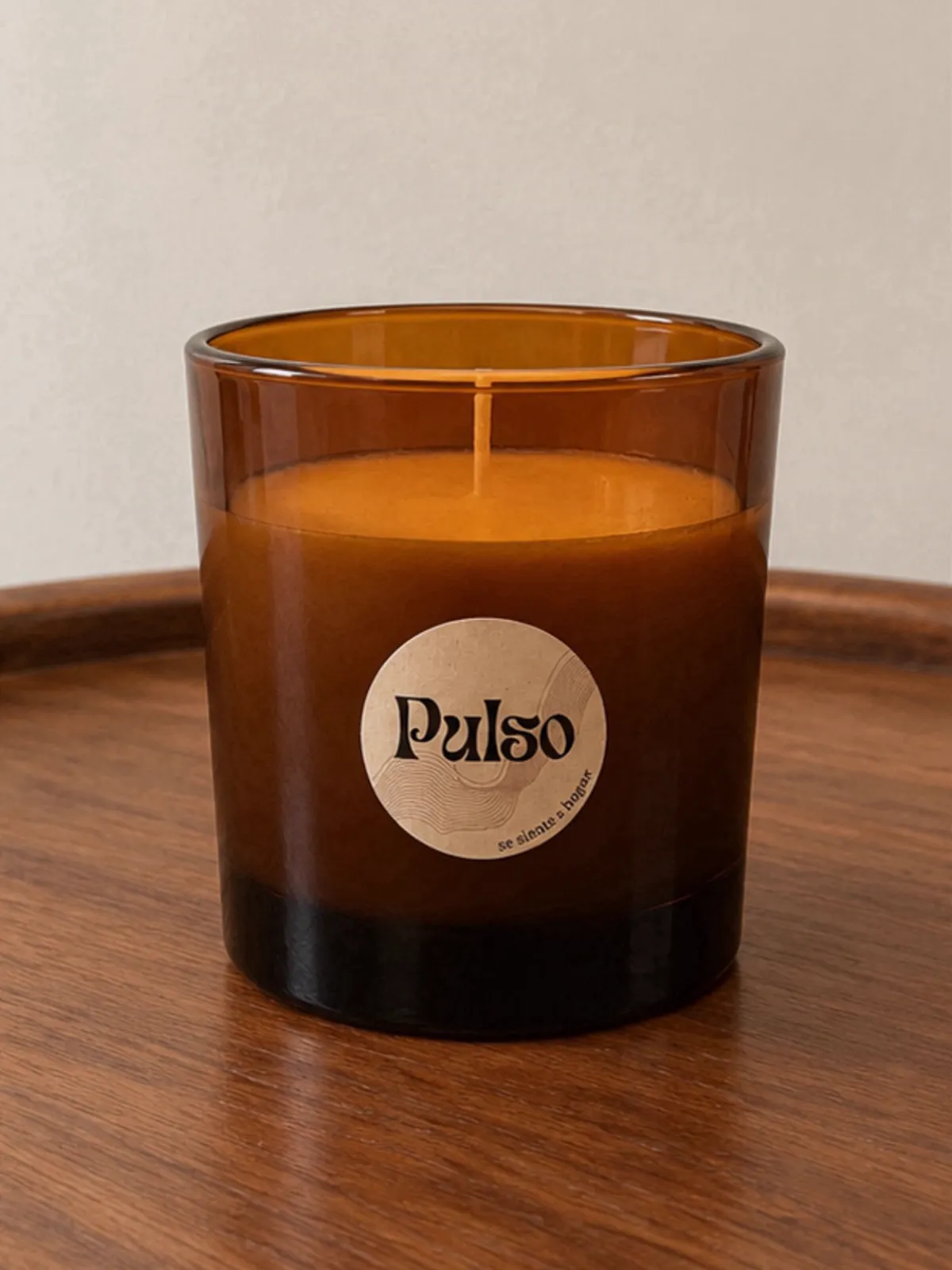 Vela en vaso de vidrio ámbar con la etiqueta circular de Pulso