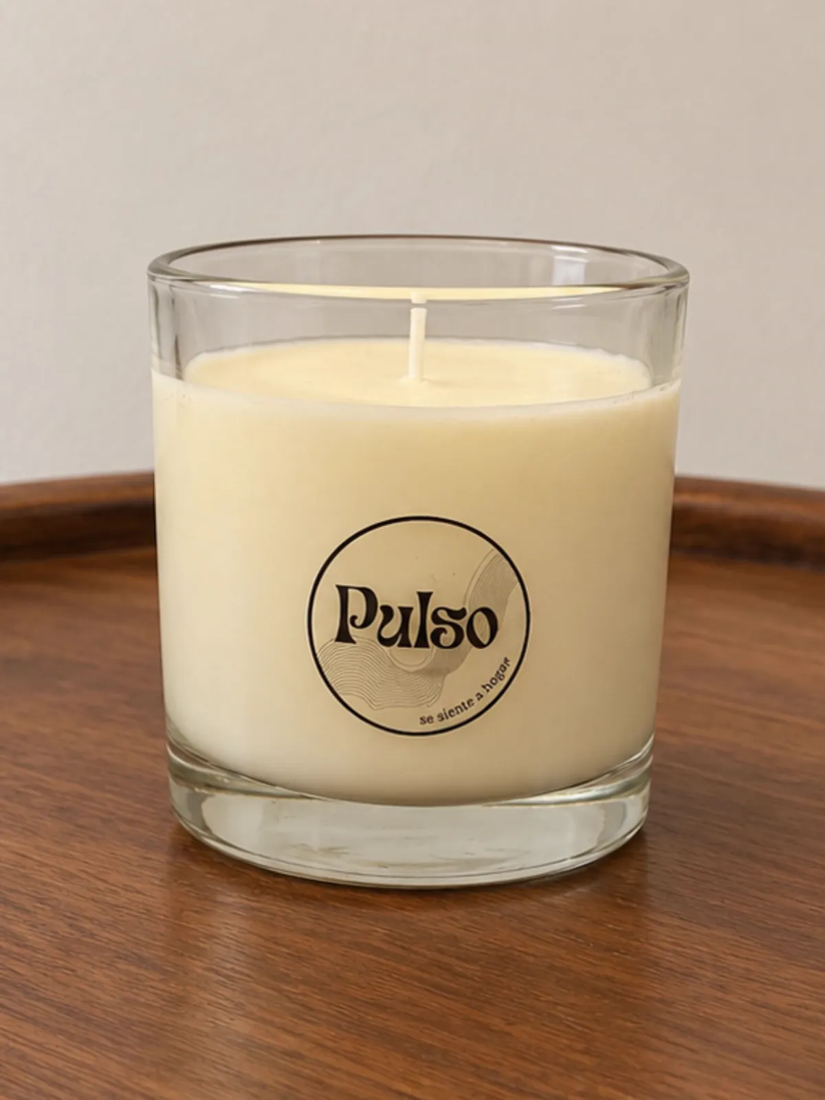 Vela blanca en vaso transparente con la etiqueta circular de Pulso